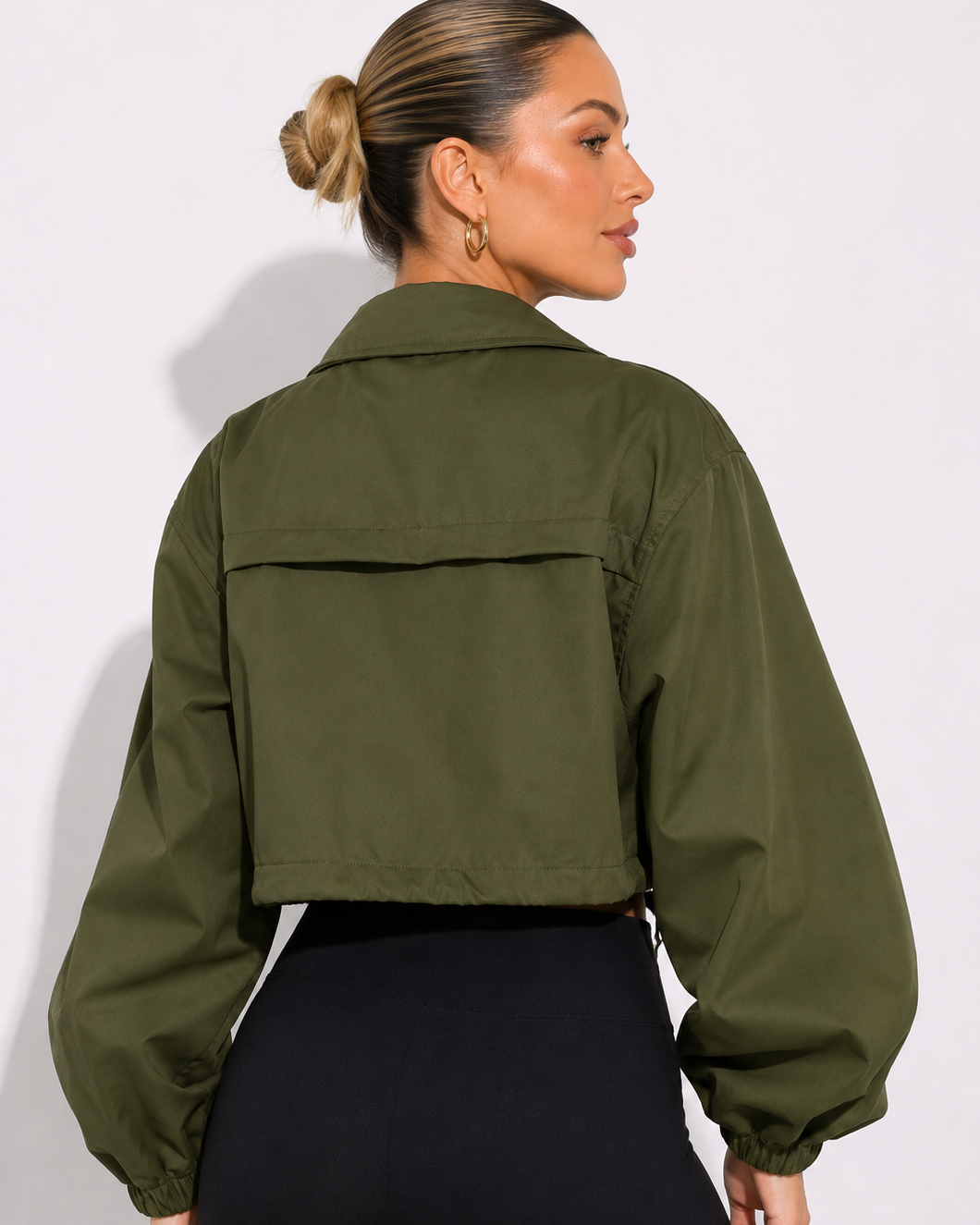 Person wearing an olive green jacket on a plain background