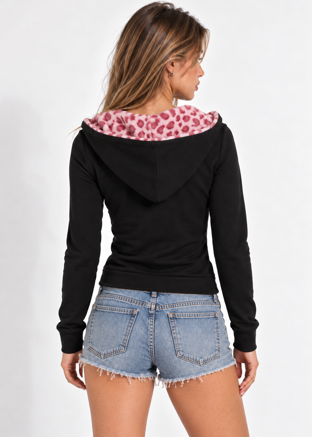 Roxie black zip-up hoodie with lowered pink leopard-lined hood, styled with denim shorts, back view