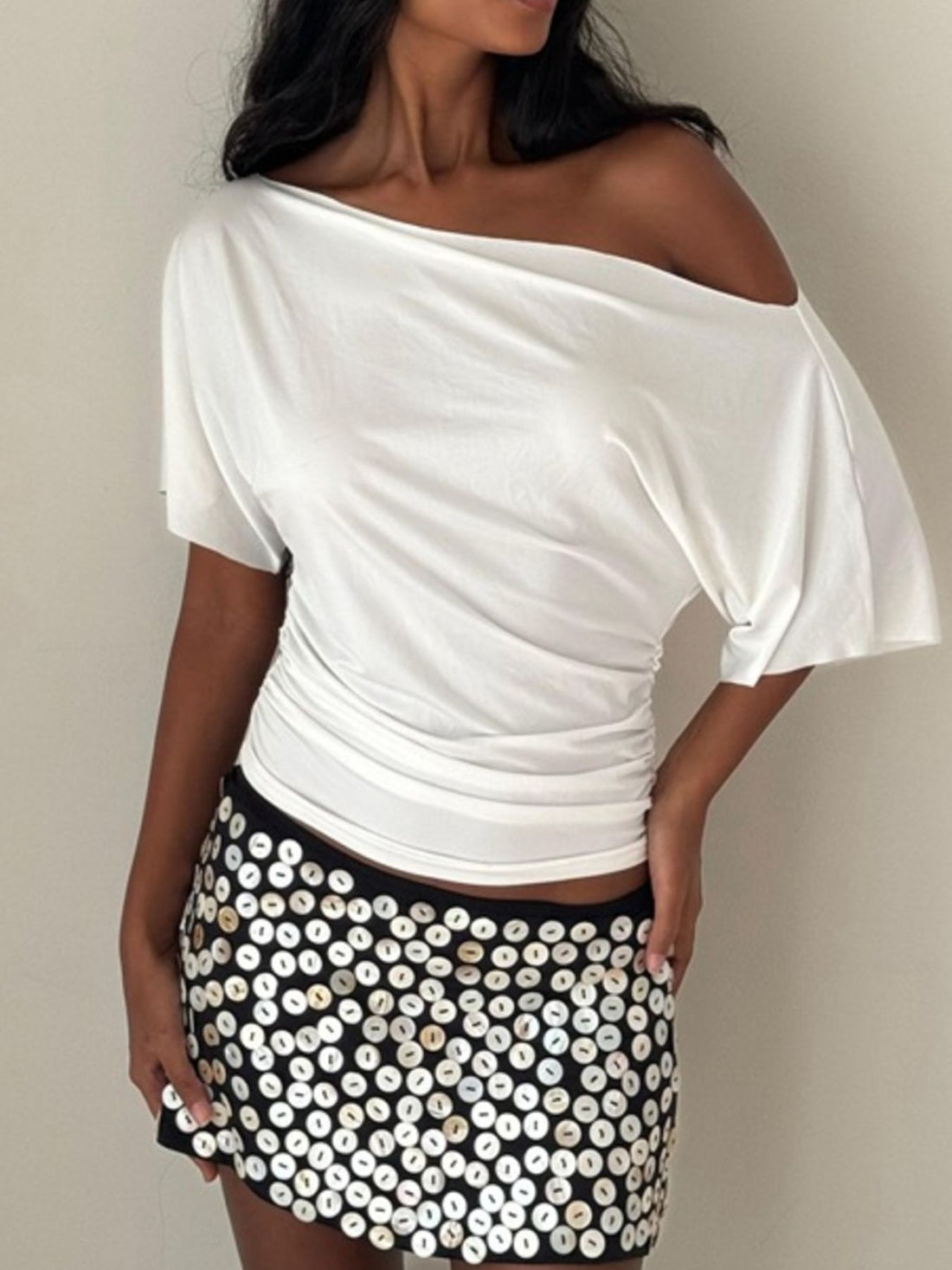 Woman wearing a green off-shoulder top against a white background