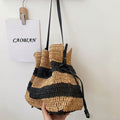 Hand holding the Calla striped woven drawstring bag by its black shoulder strap