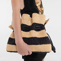 Calla black and tan striped woven bag carried under the arm with a black dress