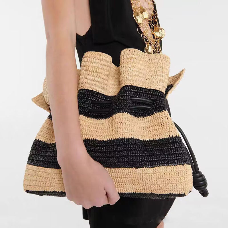 Calla black and tan striped woven bag carried under the arm with a black dress