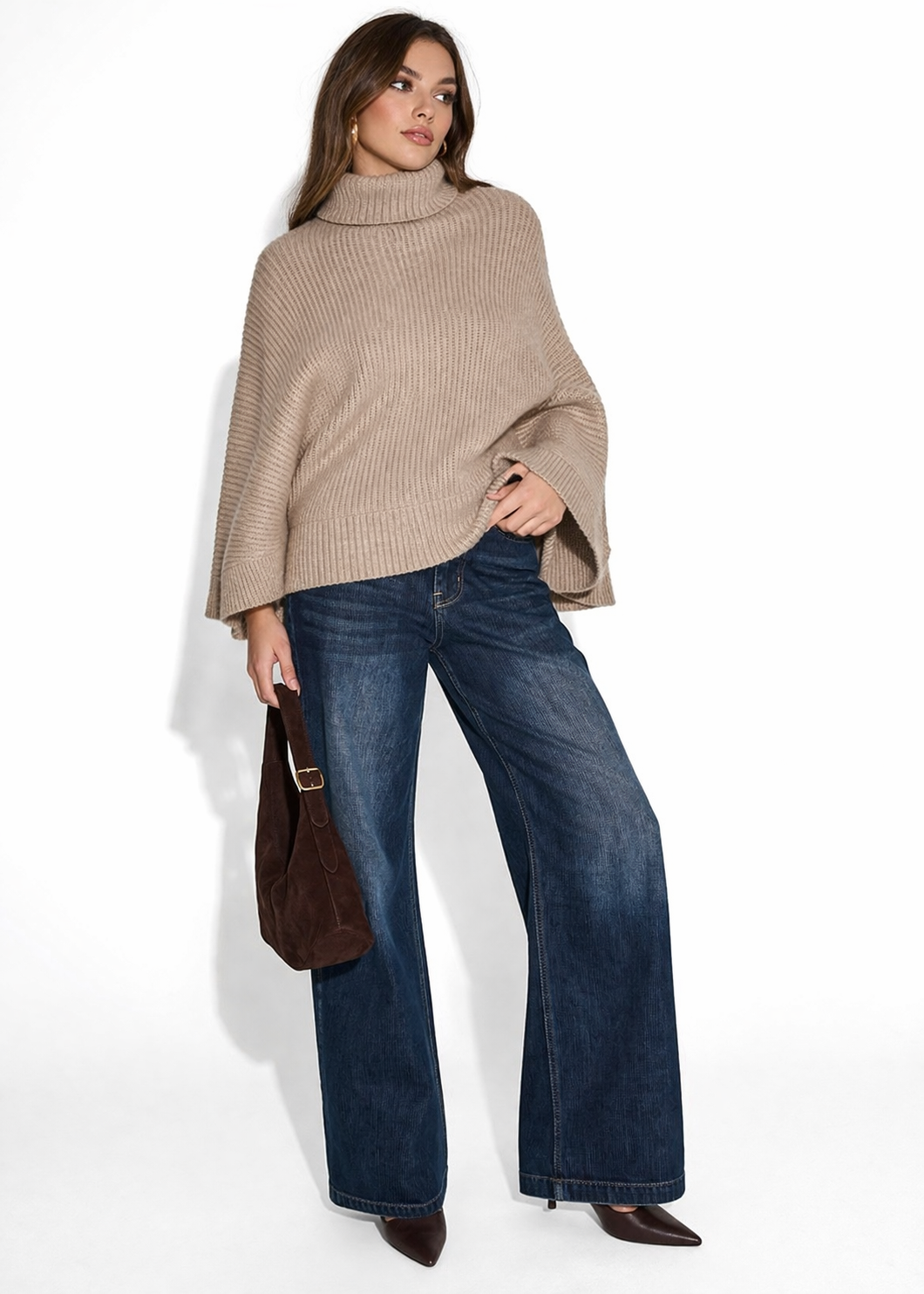 Woman wearing a BCBG Women's Oversized Turtleneck Sweater Poncho and blue jeans on a white background