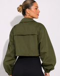 Person wearing an olive green jacket on a plain background