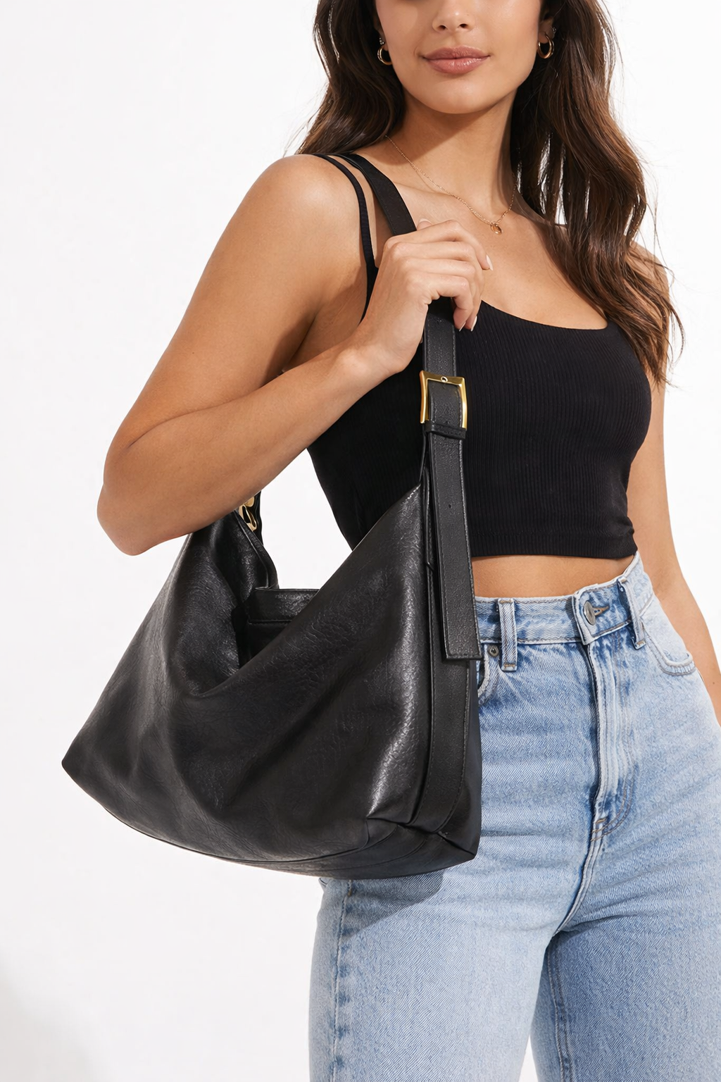 Woman holding a black leather handbag against a white background