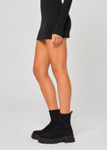Woman wearing a black dress and black boots on a white background