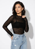Model wearing the leopard print sheer mesh top with a black bandeau and light jeans