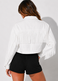 Person wearing a white fringe jacket and black shorts on a light gray background