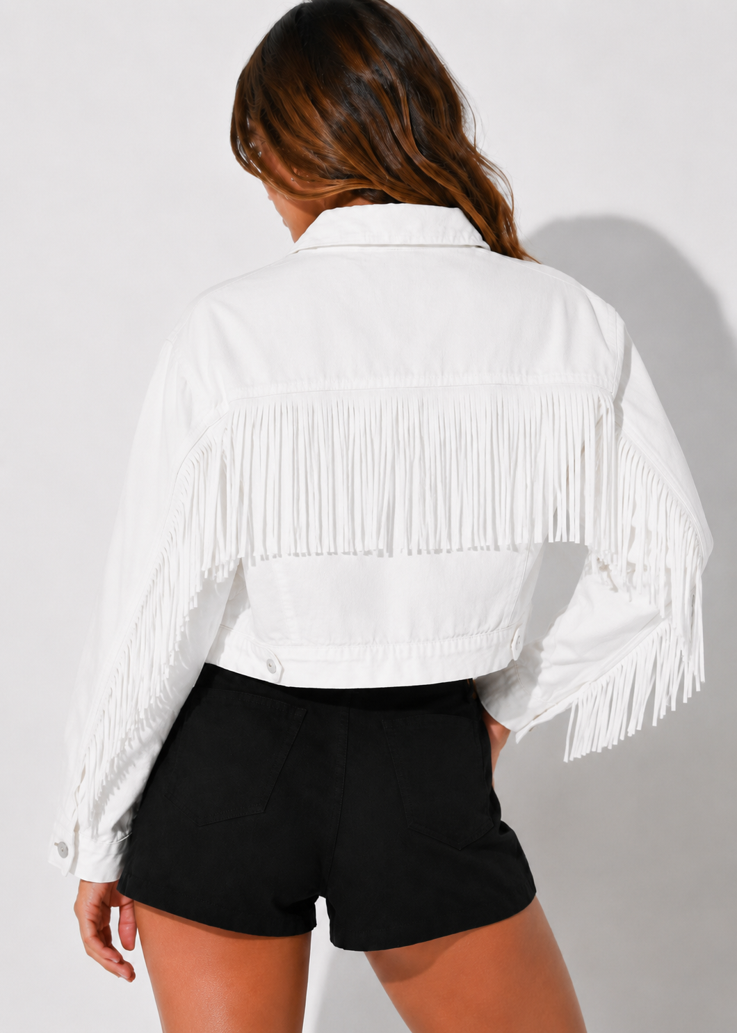 Person wearing a white fringe jacket and black shorts on a light gray background