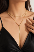 Close-up of black plunge top with layered gold necklace
