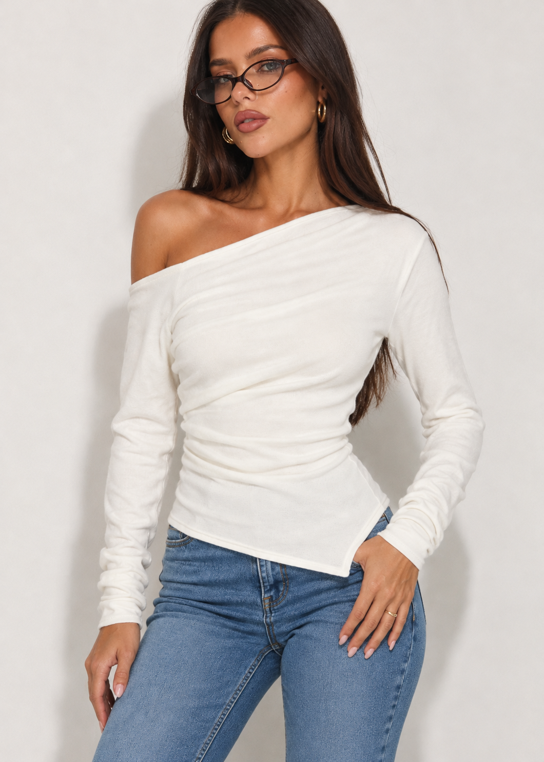 Briella white one-shoulder long sleeve top styled with blue jeans and black glasses