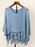 Mercantile light blue silk blouse showing tiered raw-edge front hem