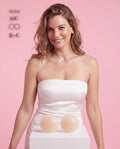 Model in a white strapless top holding Sticky Boobs silicone covers, size B-C