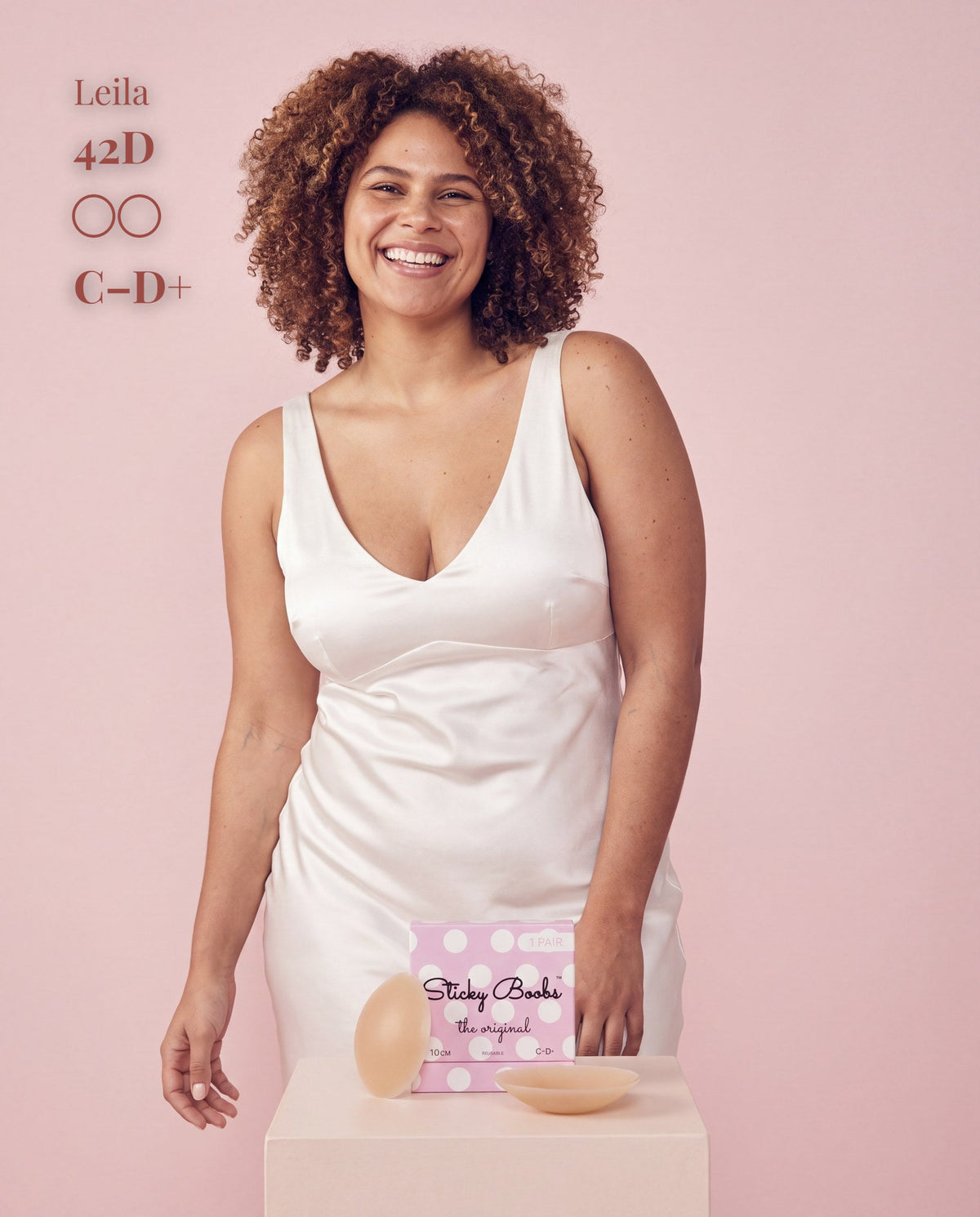 Smiling model in a white satin dress with Sticky Boobs covers for C-D+ cups