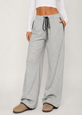 Person wearing gray wide-leg pants with a white top on a light background