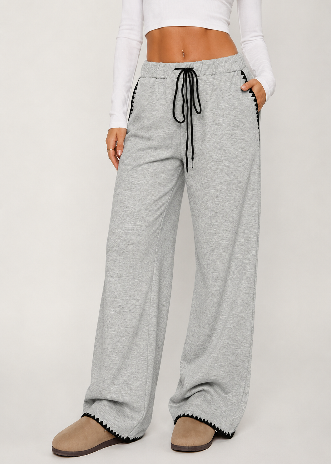 Person wearing gray wide-leg pants with a white top on a light background